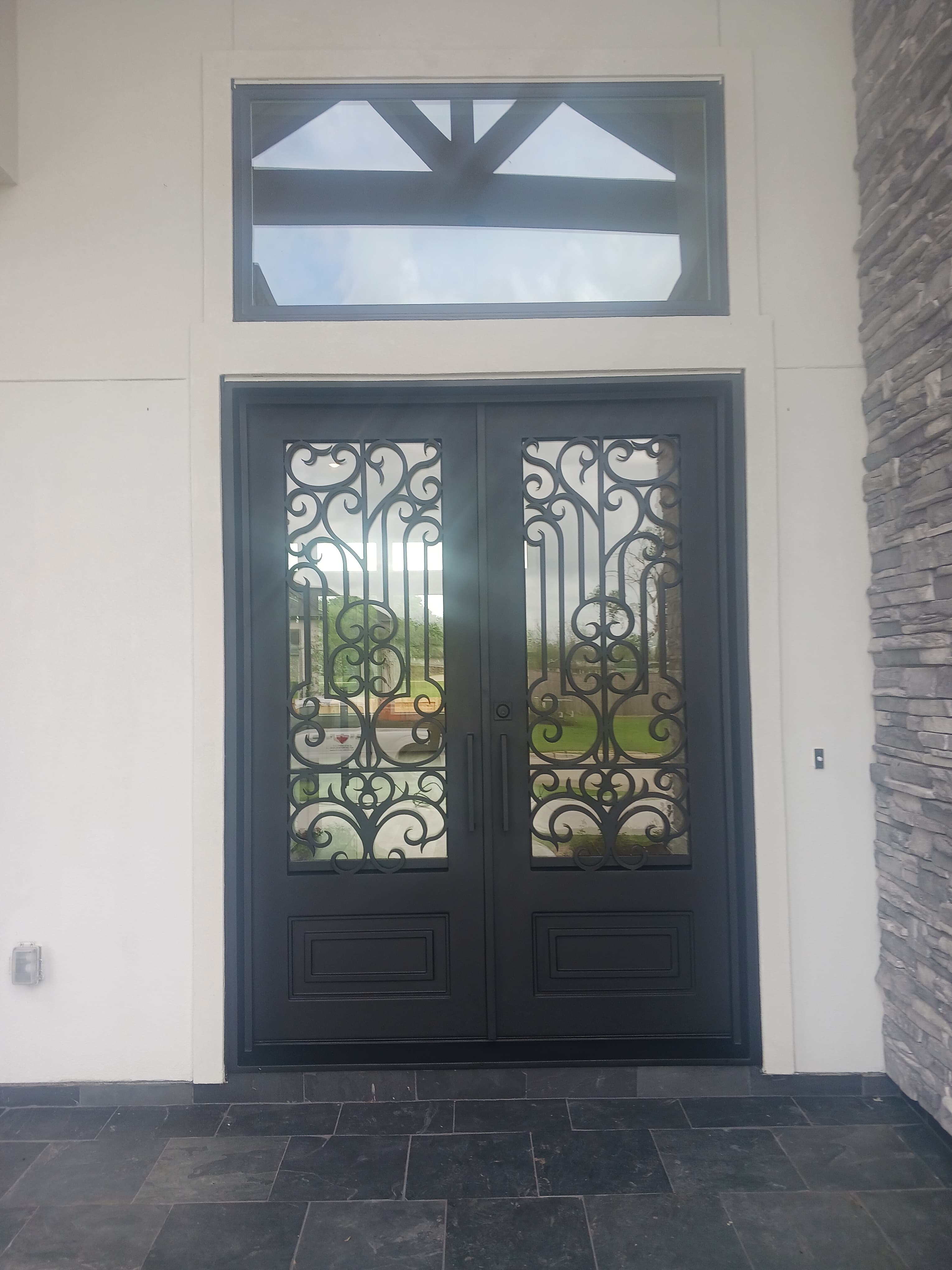 Ornate wrought iron double door with transom